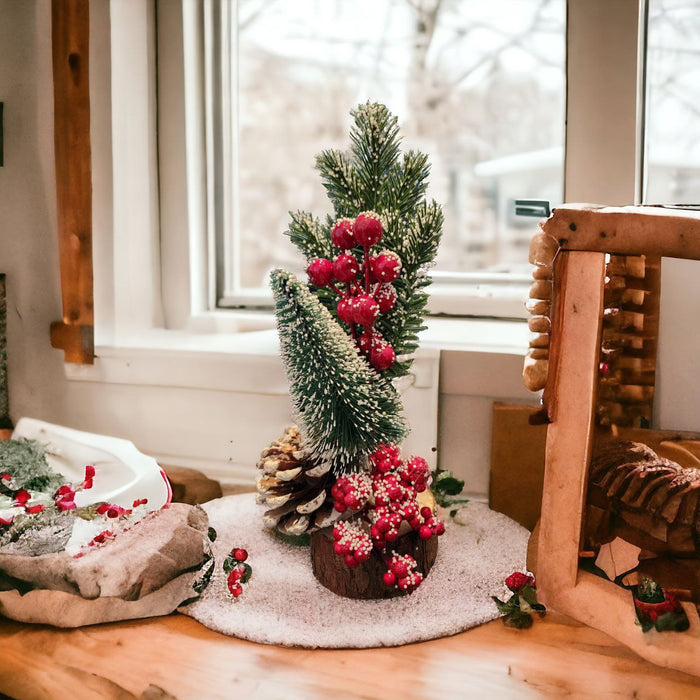 A small christmas tree with red berries and pine cones